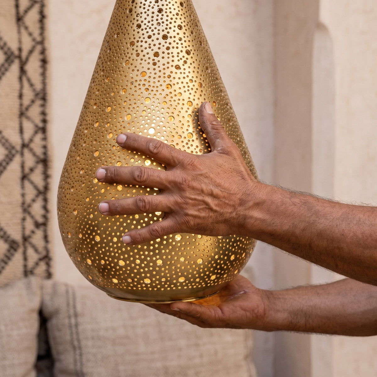 The maker's hands holding the Tichka dome, punch marks visible in the brass