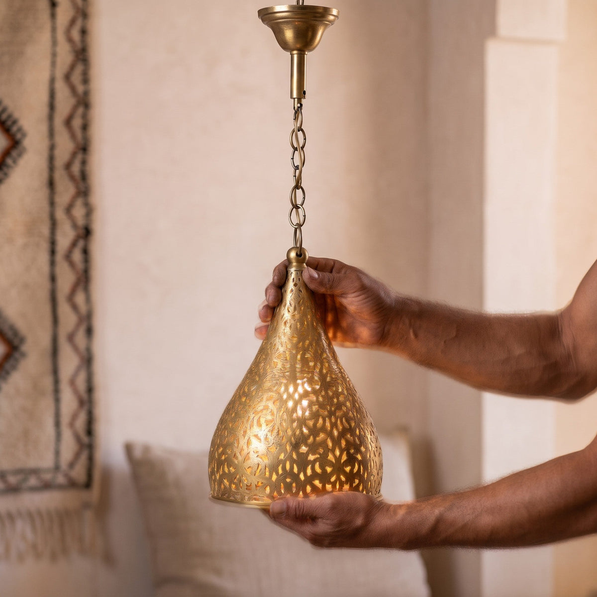 Maker's hands holding the small pierced cone of the Tizi pendant