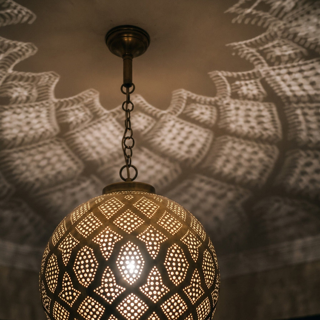 Close view of the lit Tiziri pendant, glow passing through hand-punched circles