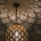 Close view of the lit Tiziri pendant, glow passing through hand-punched circles