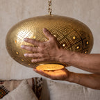 The Tudert brass shade held in the maker's hands