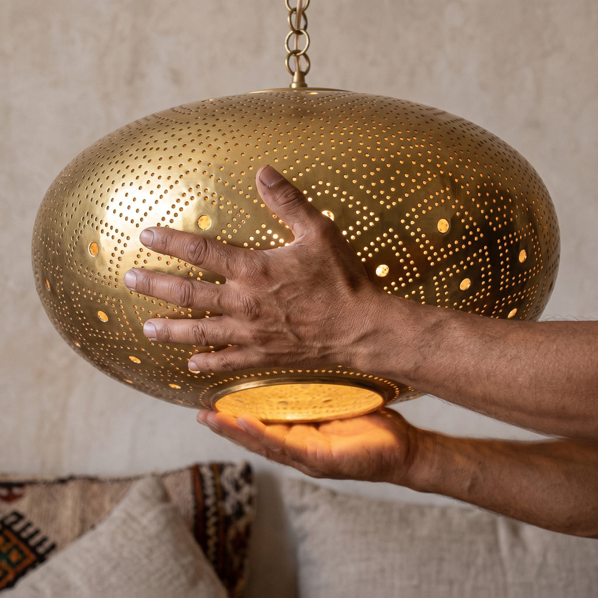 The Tudert brass shade held in the maker's hands