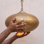 Artisan holding the Warda brass shade in both hands