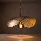 Close view of the lit Warqa pendant, hammer marks glowing on the brass rim