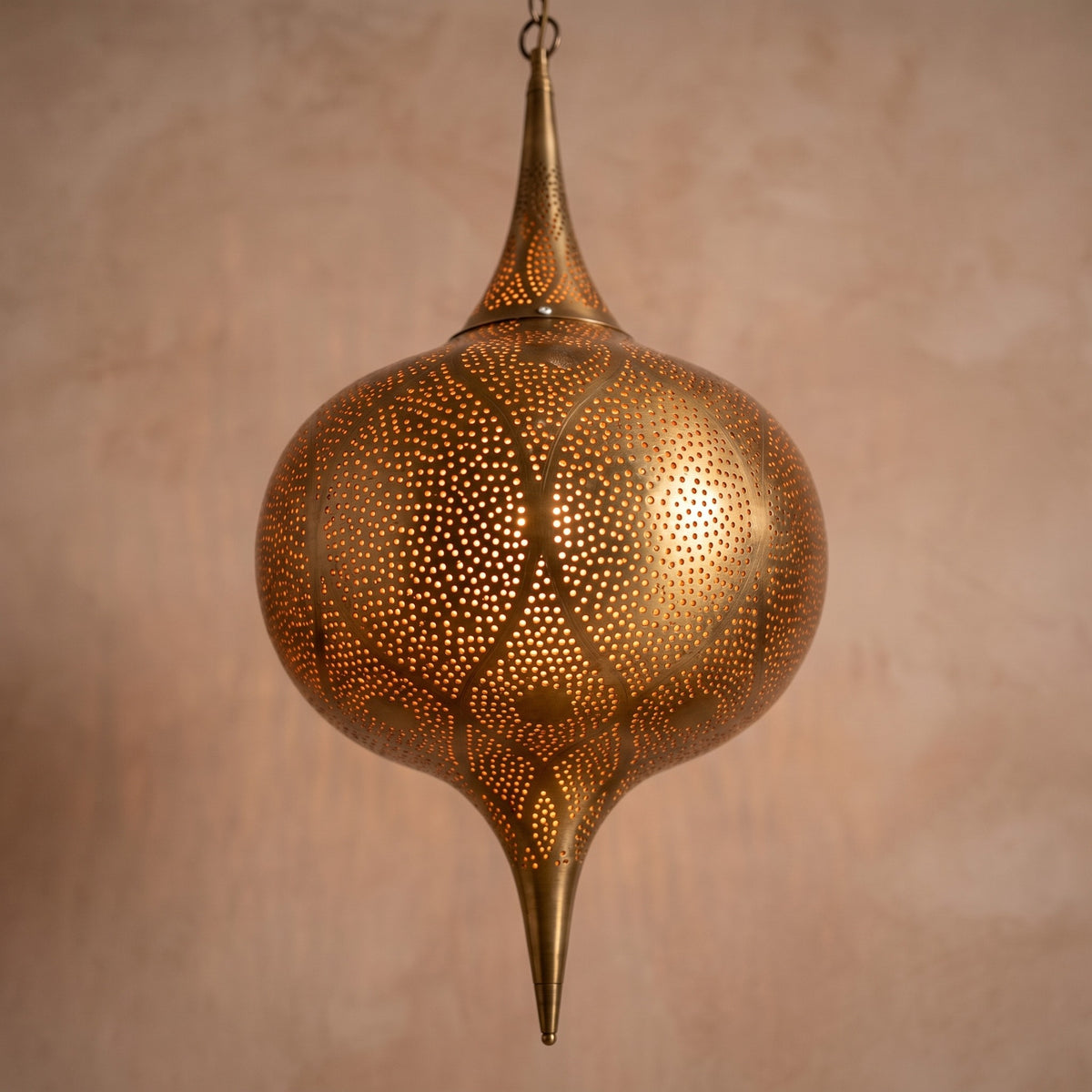 Close detail of the lit Zagora lantern hanging from its chain, punched circles glowing