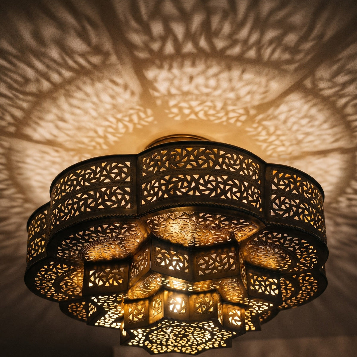 Close detail of the lit Zellige dome, geometric cuts glowing in the brass