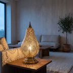 Zina table lamp lit on a wooden console in a modern living room, pattern on the wall behind
