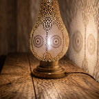 Close detail of the lit Zina lamp, light coming through the hand-pierced brass openings