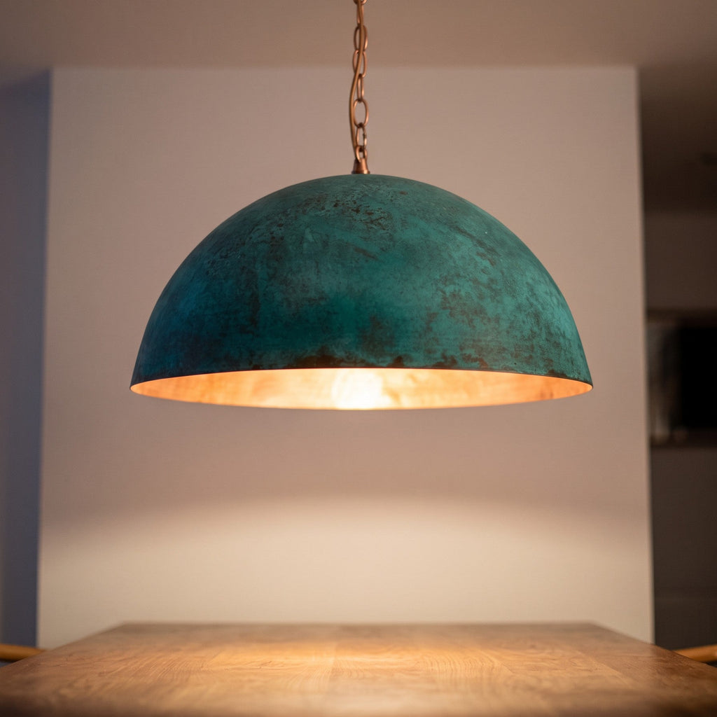 Close detail of the lit Zitoun pendant, copper interior glowing under the verdigris rim