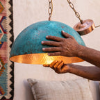 Artisan's hands holding the oxidized green dome of the Zitoun pendant