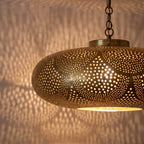 Detail of the lit Zohra pendant, bright points through the pierced brass